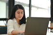 © saltdium - Portrait image of Young Asian businesswoman or female office worker working with laptop.