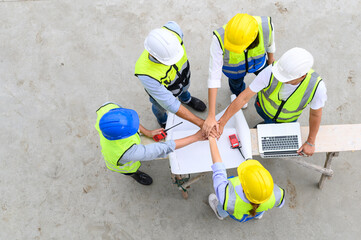 Wall Mural - Top view of contractors, engineers and formats team in safety vests with helmets working with laptops, standing on under-construction building site. Home building project. 