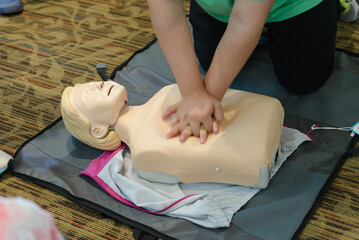 CPR First Aid Training with CPR dummy in the class. Demonstrating chest compressions concept.