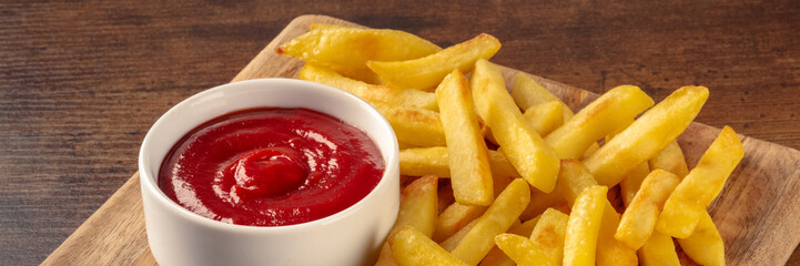 Poster - French fries, potato snack with ketchup, fast food on a wooden table, a panorama for a menu