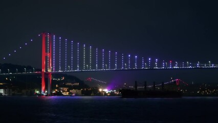 Wall Mural - View of Bosphorus Bridge at night in Istanbul, Turkey. View from a floating ship, illumination, moving on the bridge cars