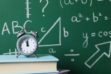 School formulas and drawings on a school blackboard with an alarm clock and books on the table