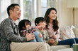 © imtmphoto - young asian family with two children watching tv together at home