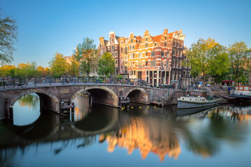 Early quiet morning in Amsterdam. Gentle sun shines the famous view of Amsterdam. Typical old houses and bridges.