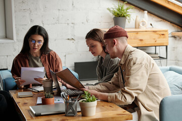 Aufkleber - Young businessman with document making presentation while sitting next to his colleague at meeting and explaining her data on laptop screen