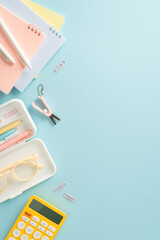 Unlock your full potential with top vertical view composition of impressive range of stationery essentials, notepads and calculator against blue backdrop, empty space for adding text or promotion