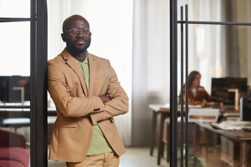 Aufkleber - Young confident businessman in formalwear standing in door of coworking area against his colleague sitting by workplace in front of computer