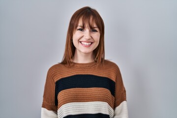 Wall Mural - Young beautiful woman wearing striped sweater over isolated background with hands together and crossed fingers smiling relaxed and cheerful. success and optimistic