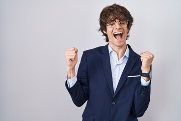 Sticker - Hispanic business young man wearing glasses celebrating surprised and amazed for success with arms raised and eyes closed. winner concept.