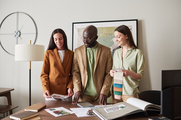 Aufkleber - three young intercultural designers looking at sketches or photos of interiors and consulting about 