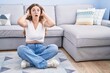 © Krakenimages.com - Young caucasian woman sitting on the floor at the living room crazy and scared with hands on head, afraid and surprised of shock with open mouth