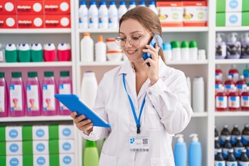 Sticker - Young blonde woman pharmacist using touchpad talking on smartphone at pharmacy