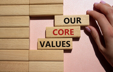 Our core values symbol. Concept words Our core values on wooden blocks. Beautiful pink background. Businessman hand. Business and Our core values concept. Copy space.