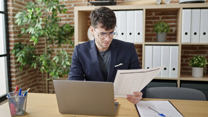 Poster - Young hispanic man business worker using laptop reading document at office