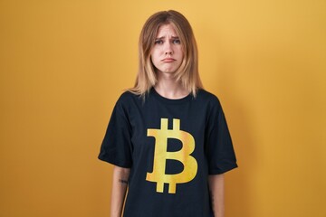 Wall Mural - Blonde caucasian woman wearing bitcoin t shirt depressed and worry for distress, crying angry and afraid. sad expression.