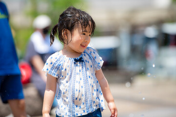 Poster - 広場の噴水で水遊びしている3歳の女の子