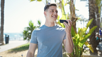 Poster - Young hispanic man tourist sending voice message with smartphone at seaside