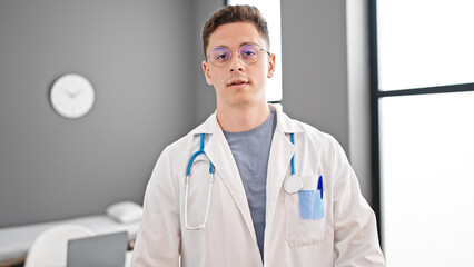 Wall Mural - Young hispanic man doctor standing with serious expression at clinic