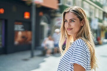 Wall Mural - Young blonde woman smiling confident looking to the side at street