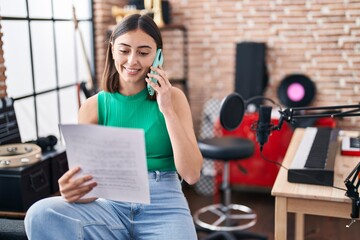 Wall Mural - Young hispanic woman musician talking on the smartphone at music studio