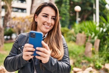 Young beautiful hispanic woman smiling confident using smartphone at park