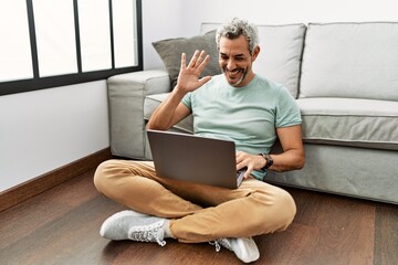 Wall Mural - Middle age grey-haired man having video call sitting on floor at home