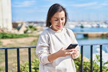 Poster - Middle age woman smiling confident using smartphone at seaside