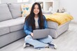 © Krakenimages.com - Young chinese woman using laptop sitting on floor at home