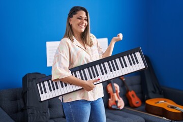 Wall Mural - Blonde woman holding piano keyboard screaming proud, celebrating victory and success very excited with raised arm