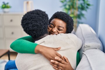 Poster - African american man and woman couple hugging each other sitting on sofa at home