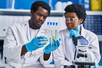 Canvas Print - African american man and woman scientists holding test tubes at laboratory