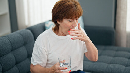 Wall Mural - Middle age woman drinking glass of water coughing home