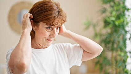 Wall Mural - Middle age woman combing hair at bedroom