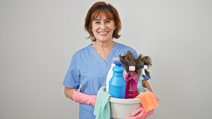 Sticker - Middle age woman professional cleaner holding basket with clean products over isolated white background