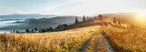 Fototapeta Na ścianę - Mountain autumn landscape. Grassy road to the mountains hills during sunset. Nature background