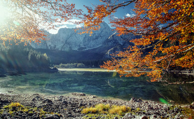 Wall Mural - Awesome alpine highlands in sunny day. Scenic image of fairy-tale lake during sunset. Majestic Rocky Mountains on background. Wild area. Fusine lake. Italy, Julian Alps. Best travel locations.