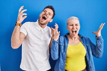 Canvas Print - Young brazilian mother and son standing over blue background celebrating mad and crazy for success with arms raised and closed eyes screaming excited. winner concept