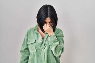 Poster - Young asian woman standing over white background tired rubbing nose and eyes feeling fatigue and headache. stress and frustration concept.