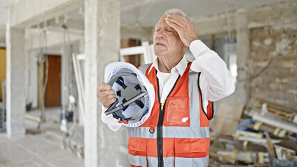 Sticker - Senior grey-haired man architect using hardhat as a hand fan at construction site