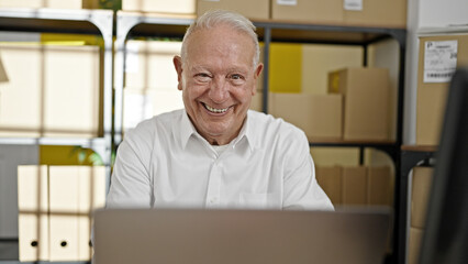 Canvas Print - Senior grey-haired man ecommerce business worker using laptop sitting with arms crossed gesture at office