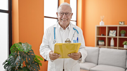 Sticker - Senior grey-haired man doctor reading document on clipboard at clinic