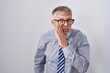 © Krakenimages.com - Hispanic business man with grey hair wearing glasses hand on mouth telling secret rumor, whispering malicious talk conversation