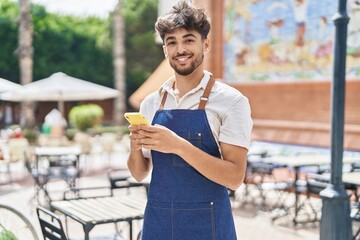 Canvas Print - Young arab man waiter using smartphone working at restaurant