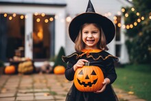 Little Girl In Witch Costume Holding Jack-o-Lantern Pumpkins On Halloween Trick Or Treat 