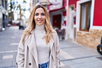 Wall Mural - Young blonde woman smiling confident standing at street