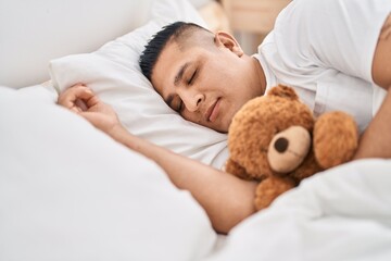 Sticker - Young latin man hugging teddy bear lying on bed sleeping at bedroom