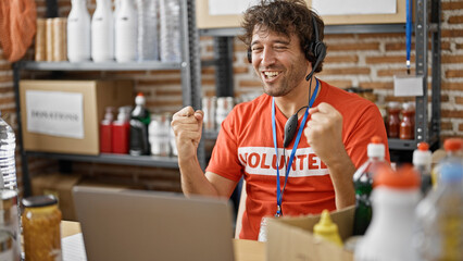 Canvas Print - Young hispanic man volunteer having video call with winner gesture at charity center