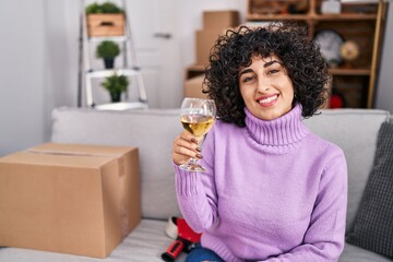 Canvas Print - Young middle east woman smiling confident drinking glass of wine at new home