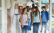 © jovannig - Multi ethnic schoolmates walking in the school hallway