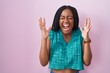 © Krakenimages.com - Young african american with braids standing over pink background celebrating mad and crazy for success with arms raised and closed eyes screaming excited. winner concept